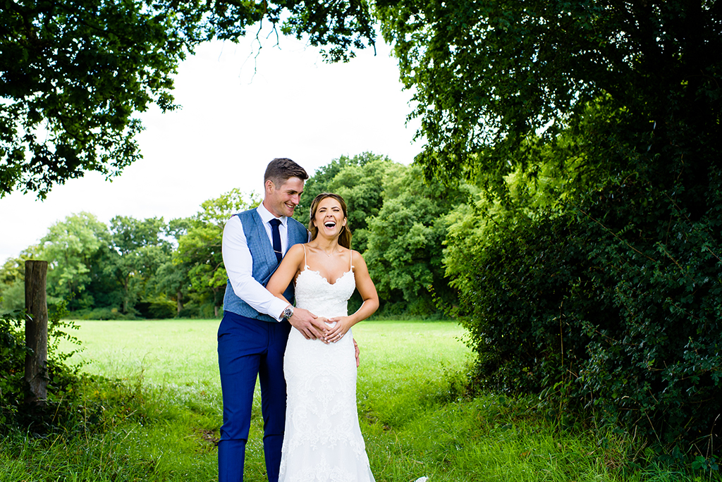 bride and groom laugh in hertfordshire countryside