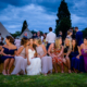 bride and friends sit on hay bale at hertfordshire tipi wedding