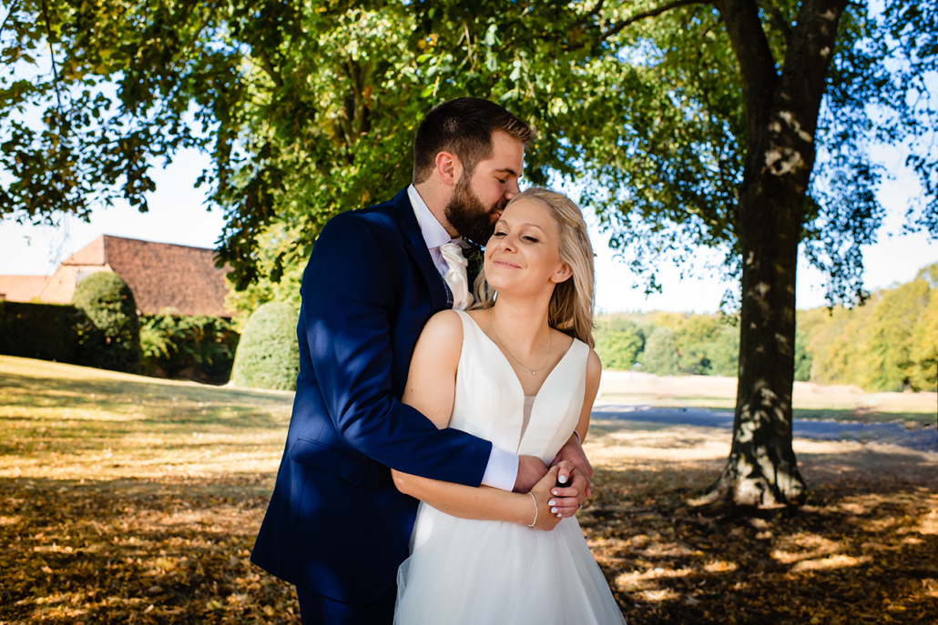 bride and groom pose at their autumn wedding at the riding school, hatfield house, hertfordshire
