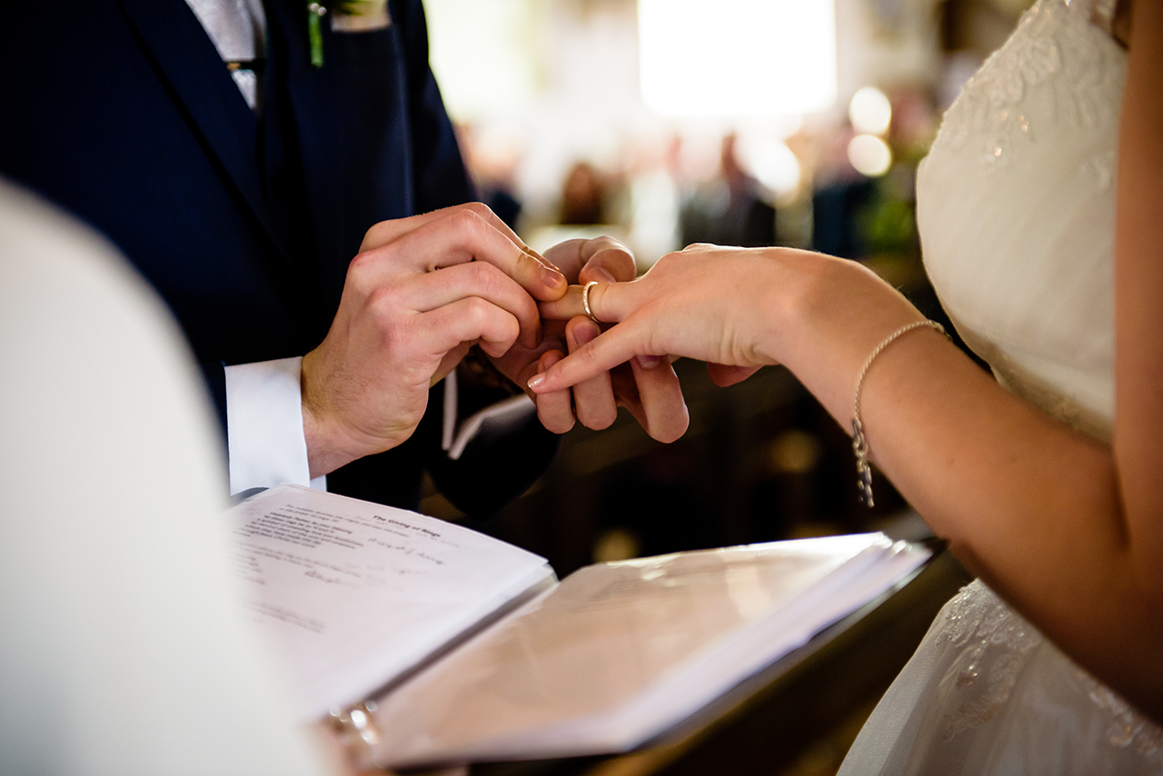 bride and groom exchange rings at St Elthandreds church in hatfield, Hertfordshire